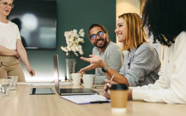 diverse people sat around a desk with a laptop on it