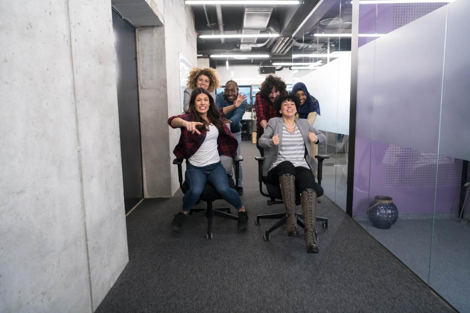 multiethnics startup business team of software developers having fun while racing on office chairs,excited diverse employees laughing enjoying funny activity at work break
