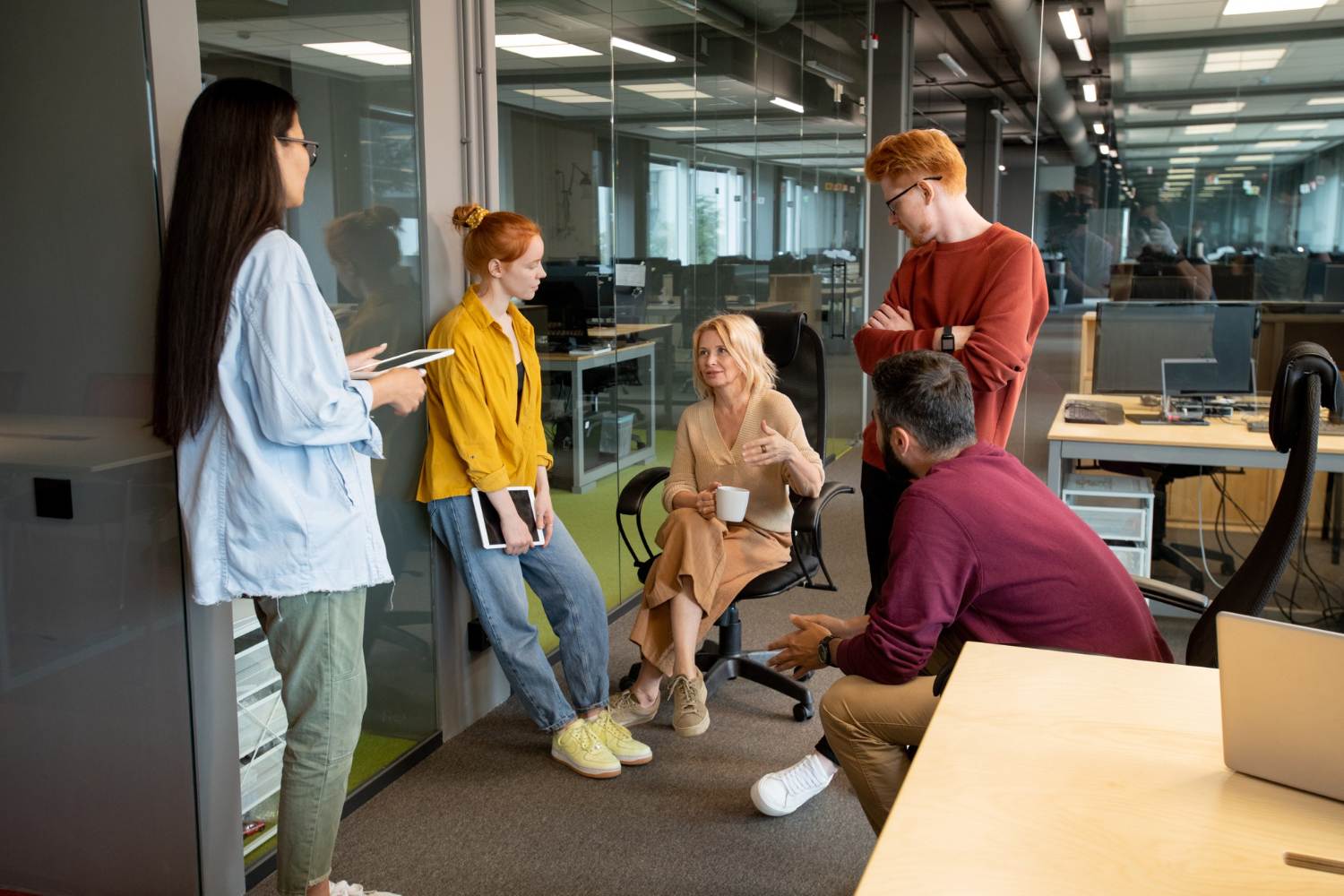 successful and confident businessmen and businesswomen in casualwear listening to mature blond female at working meeting in modern office